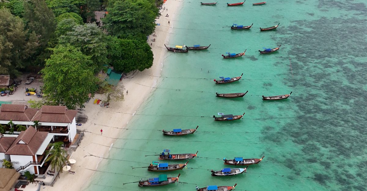 Stunning aerial view of traditional longtail boats lined up along Koh Lipe's turquoise beach.