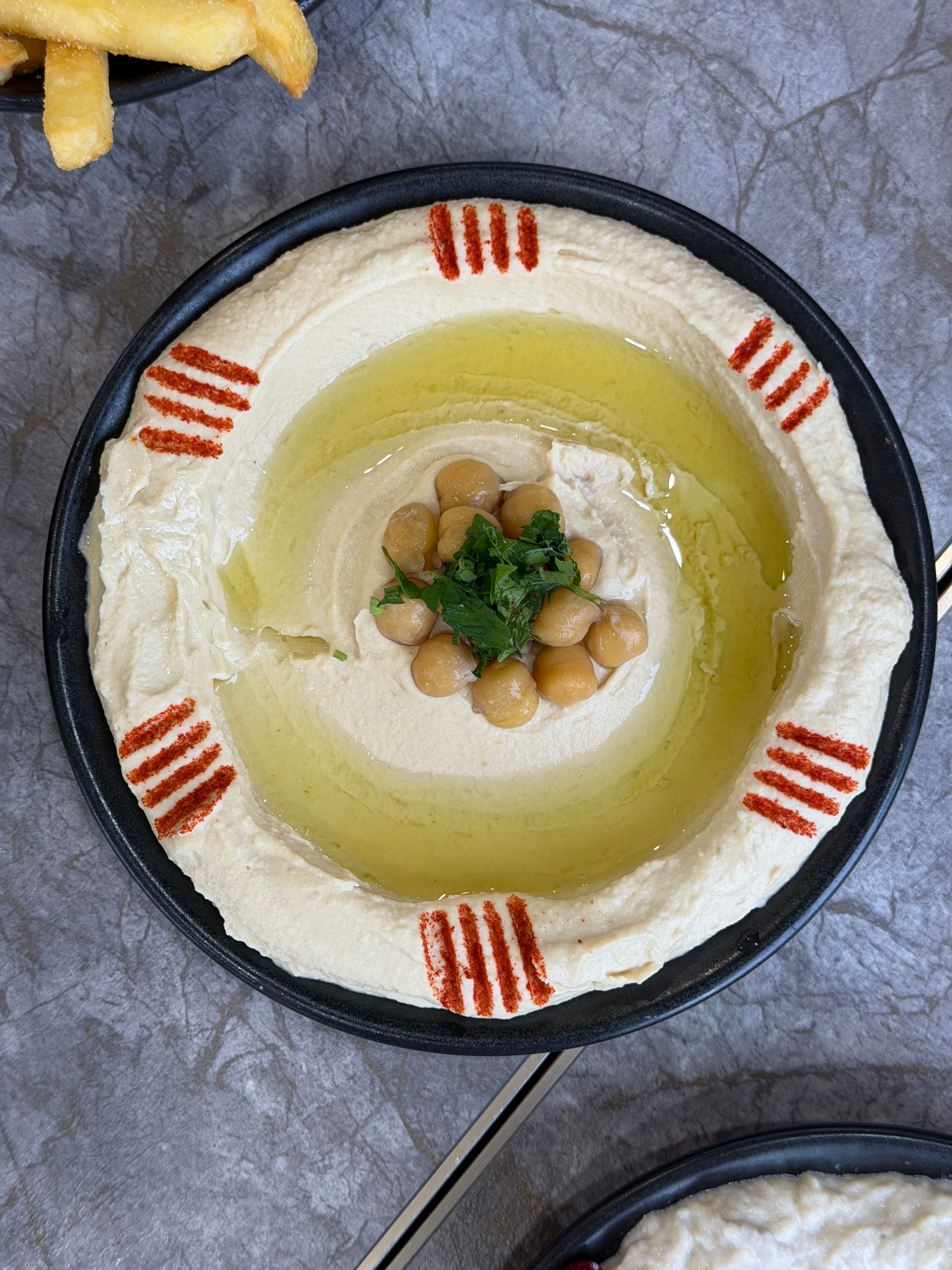 A vibrant plate of hummus garnished with chickpeas, olive oil, and paprika. Perfect for Mediterranean cuisine themes.