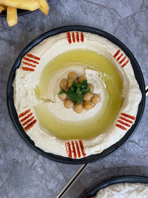 Free A vibrant plate of hummus garnished with chickpeas, olive oil, and paprika. Perfect for Mediterranean cuisine themes. Stock Photo