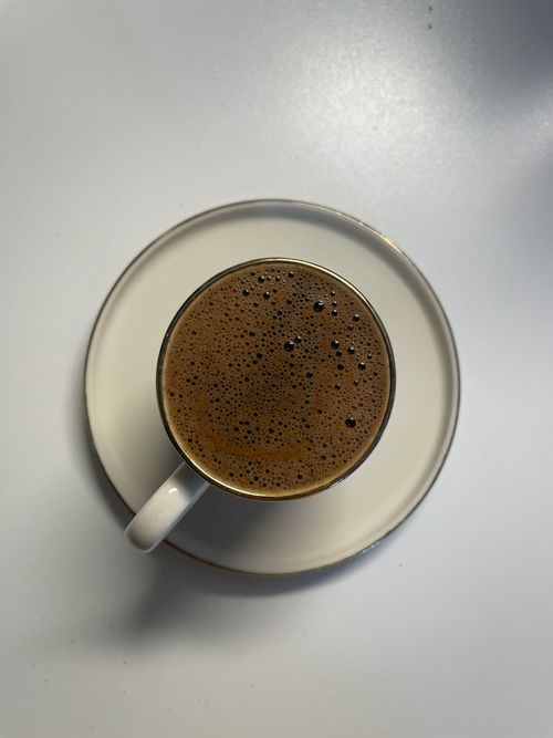 Free A steaming cup of Turkish coffee served in a white cup and saucer on a white background. Stock Photo