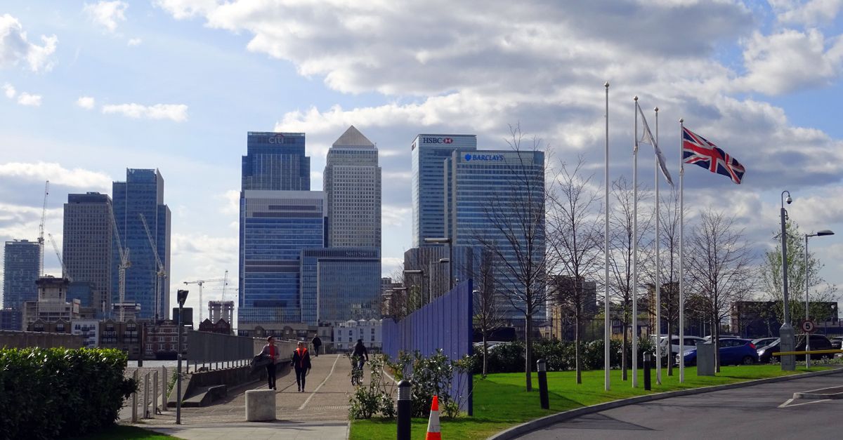 A view of the Canary Wharf skyscrapers in London, UK with a Union Jack flag in the foreground.