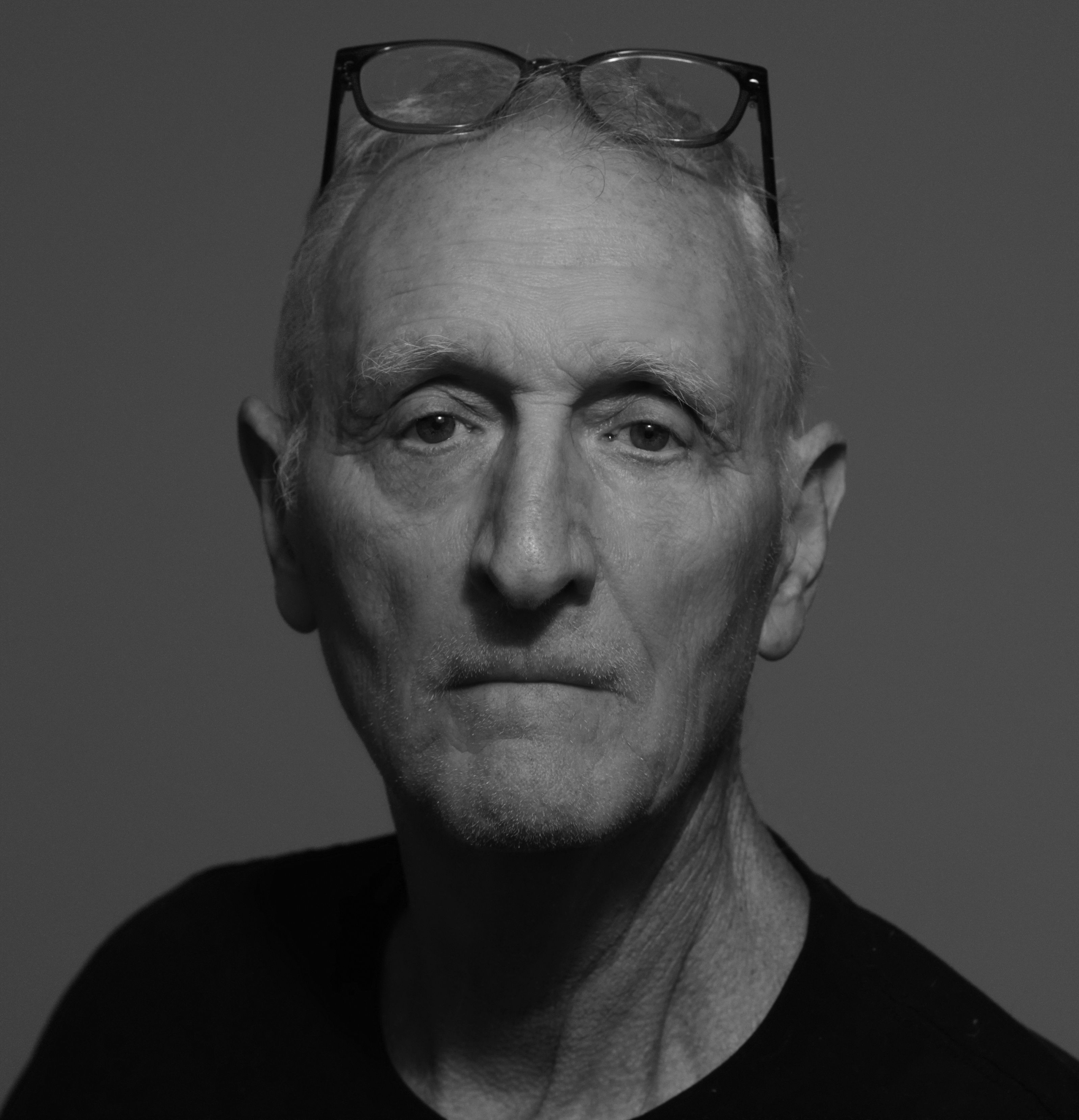 Minimalist black and white portrait of a senior man with glasses.