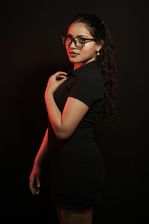 Free Elegant woman in black dress and glasses with dramatic red lighting. Stock Photo