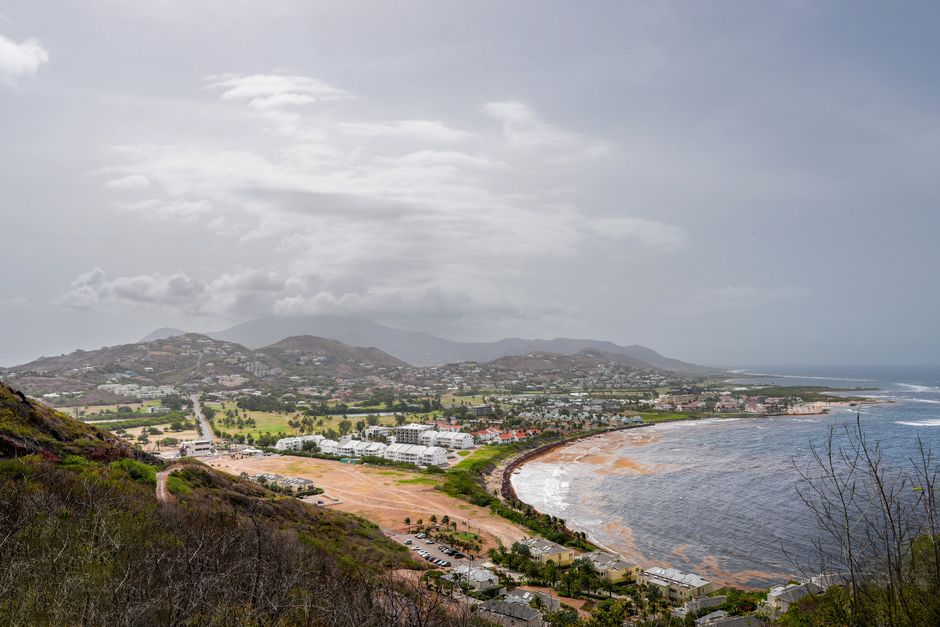 A stunning aerial view of the coastline in Saint Kitts, featuring lush hills and sprawling beaches.