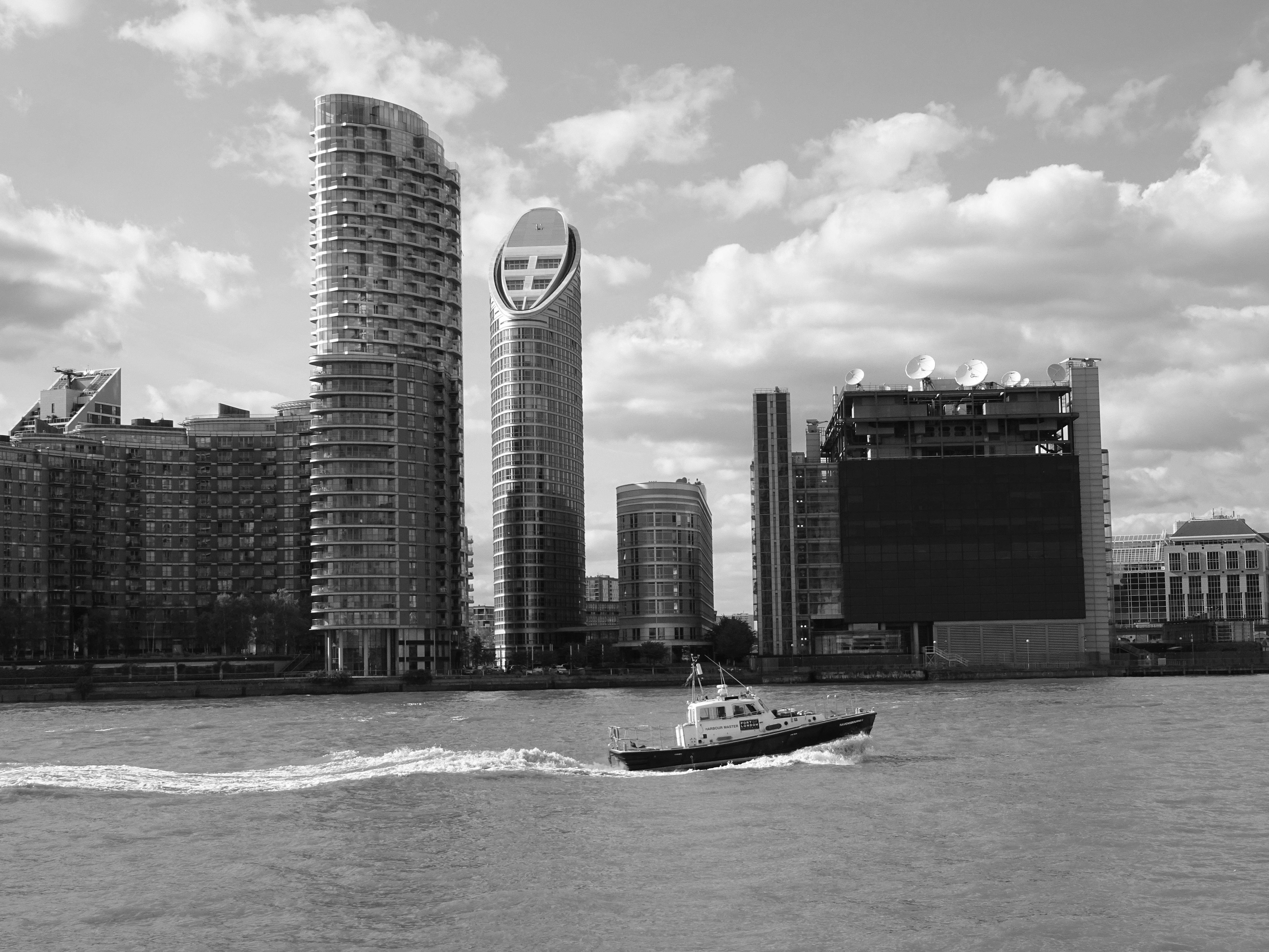 这张黑白照片展现了现代海滨的景象，其中有摩天大楼和一艘路过的船只