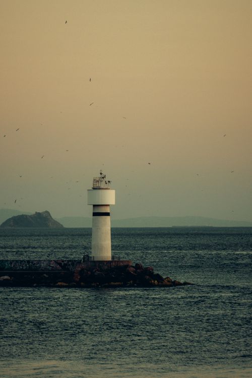 Free A tranquil view of a lighthouse standing alone at twilight against the sea. Stock Photo
