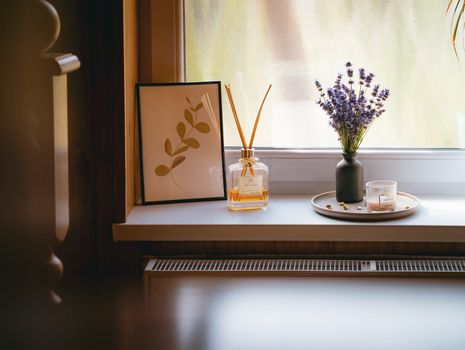 A peaceful windowsill with lavender, framed art, and aromatherapy diffuser in warm lighting.