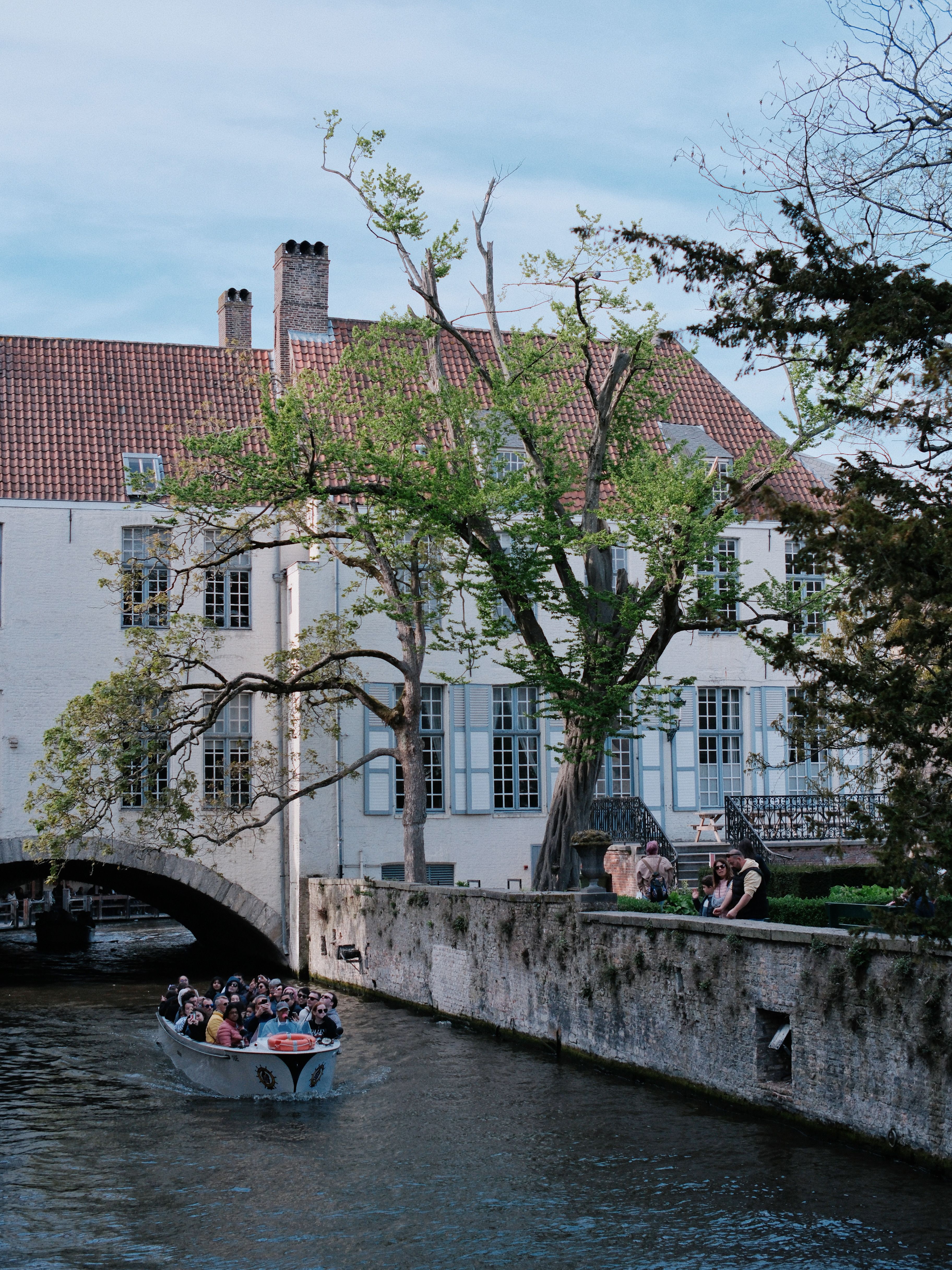 Scenic view of a canal boat tour passing by historic buildings in Bruges, Belgium.