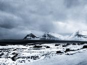 在冰岛，雄伟的雪山和海岸线映衬着戏剧性的多云天空