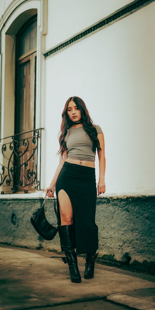 Free Stylish young woman in trendy outfit posing with confidence outdoors by an ornate door. Stock Photo