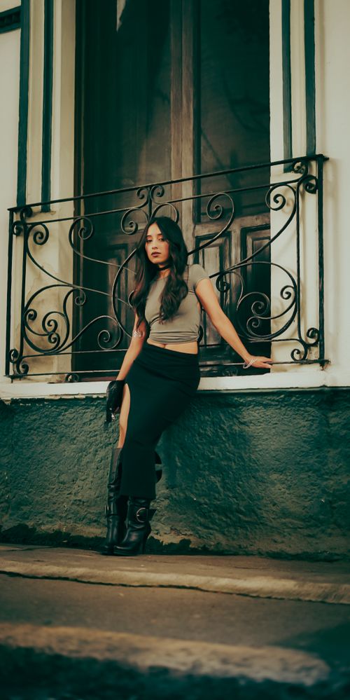 Free Fashionable woman leans against a decorative window grille, exuding urban style and elegance. Stock Photo