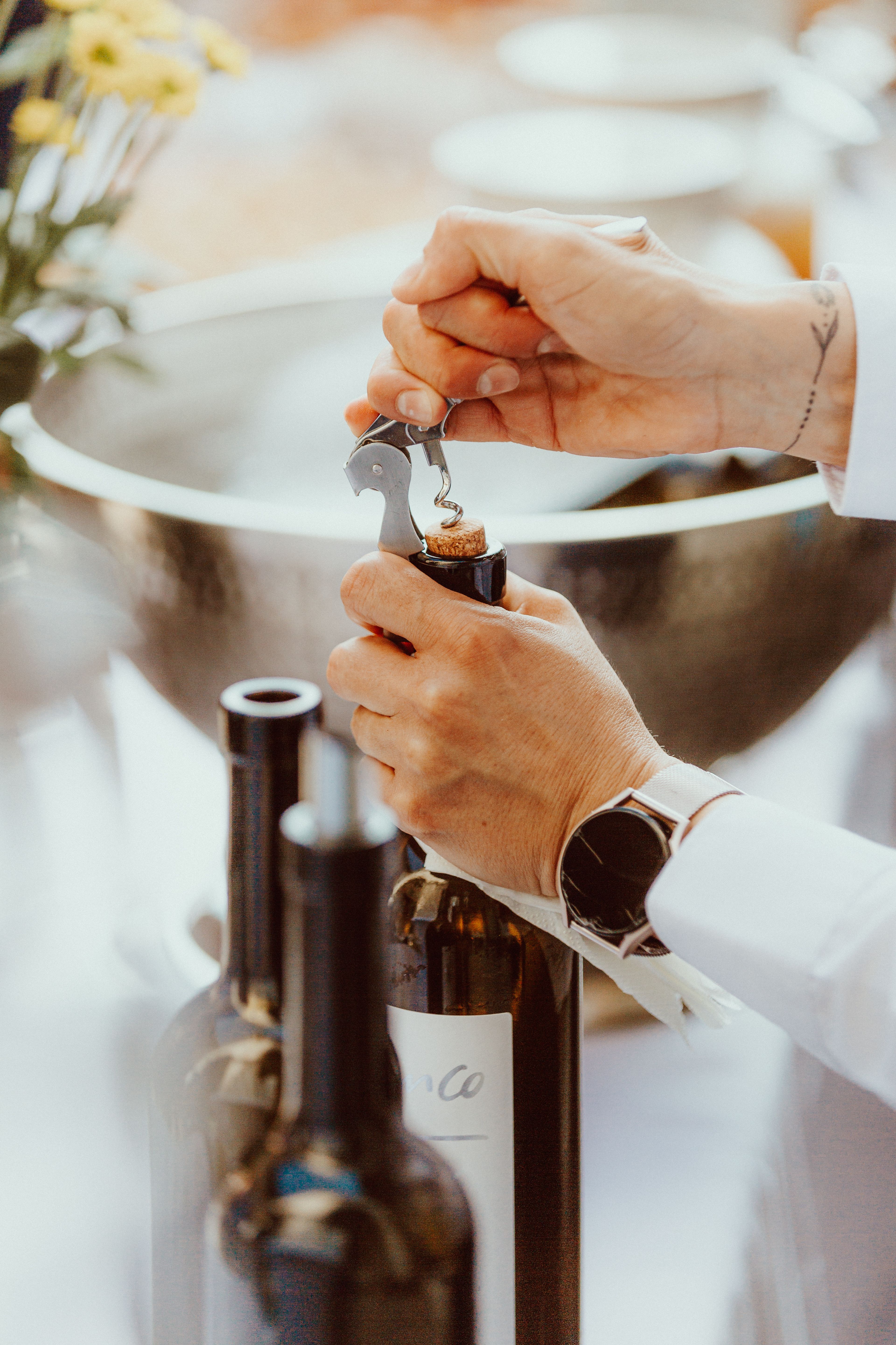 A sommelier skillfully opens a wine bottle during an elegant event.