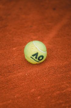 Close-up of a tennis ball on textured orange clay court, perfect for sports concepts.