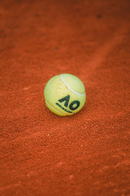 Free Close-up of a tennis ball on textured orange clay court, perfect for sports concepts. Stock Photo