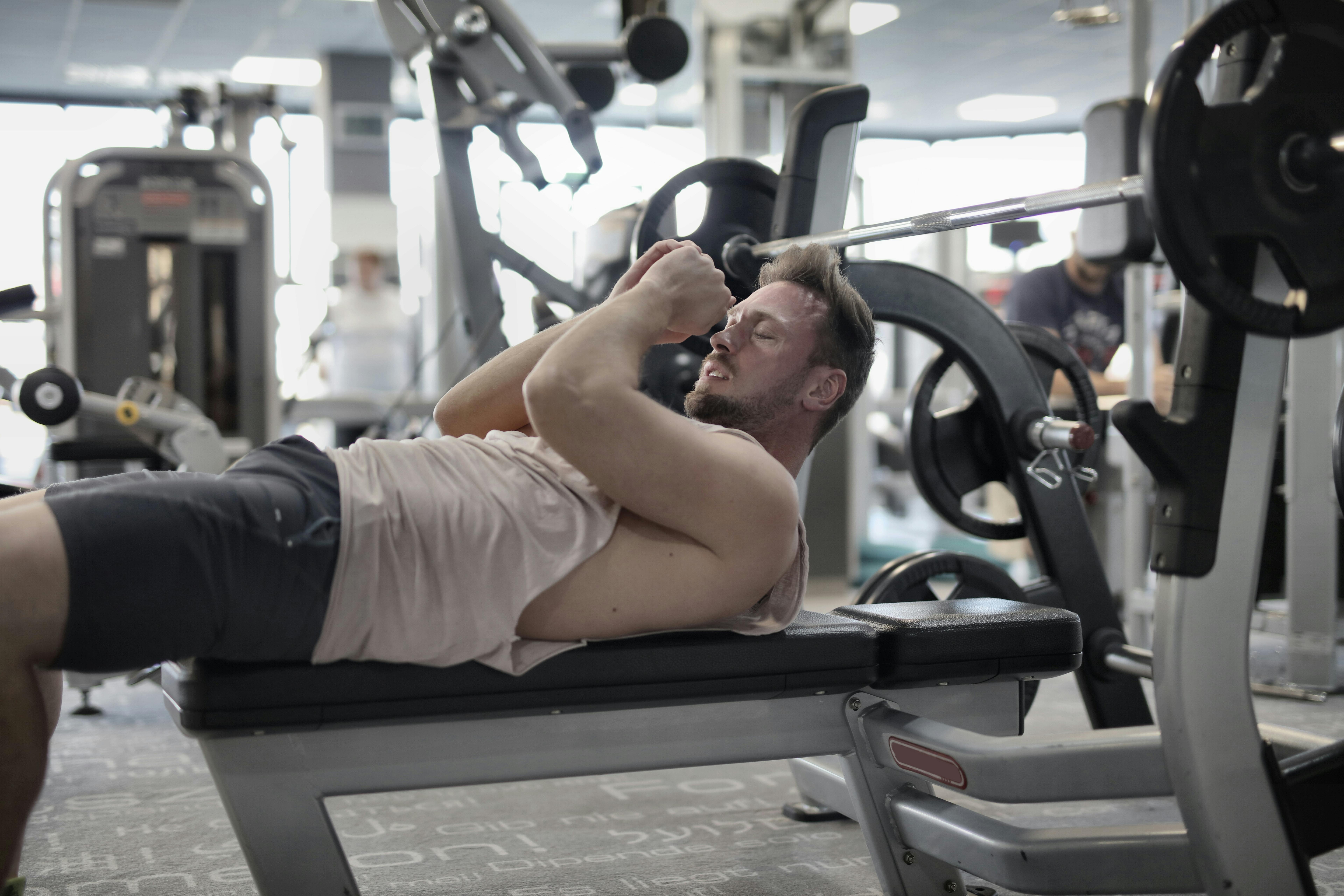 concentrated muscular sportsman preparing for bench press in gym