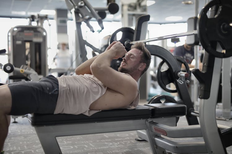 Concentrated Muscular Sportsman Preparing For Bench Press In Gym