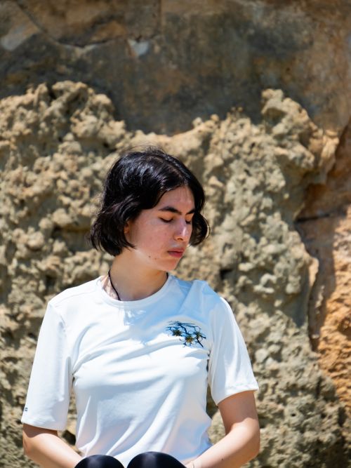 Free A young woman with short dark hair meditates outdoors, embracing tranquility against a rocky backdrop. Stock Photo