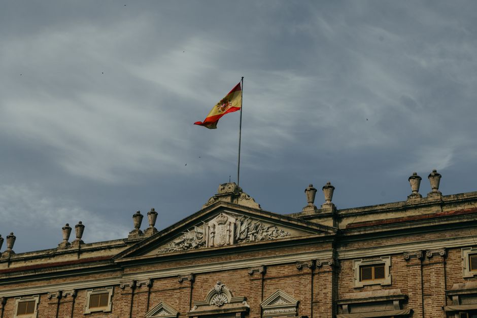 Bandera española ondeando en lo alto de un edificio histórico en Valencia, España, bajo un cielo espectacular.