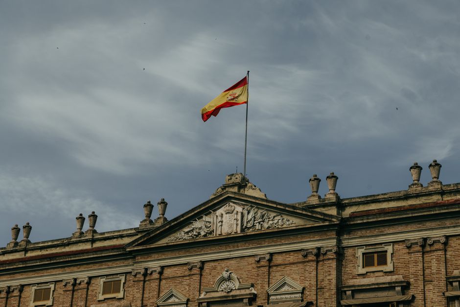 Edificio histórico con la bandera española en la cima, en Valencia, España, bajo un cielo nublado.