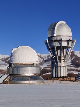 View of Tien Shan Observatory domes in the snowy mountains of Kazakhstan during winter.