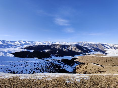 Breathtaking winter landscape in Almaty region, Kazakhstan, showcasing snow-covered mountains under a clear blue sky.