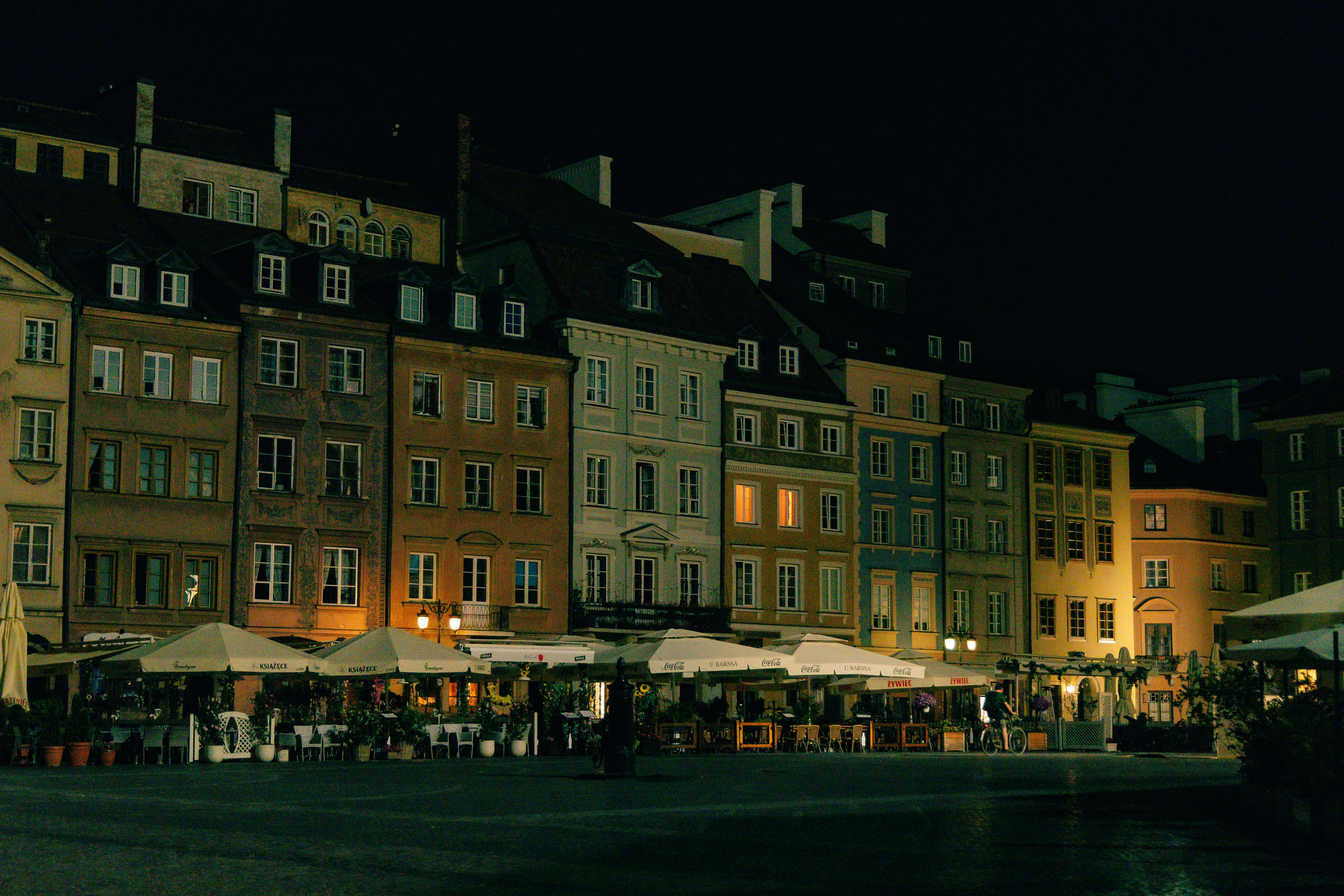 Night scene of Warsaw's Old Town Square with illuminated historic buildings.
