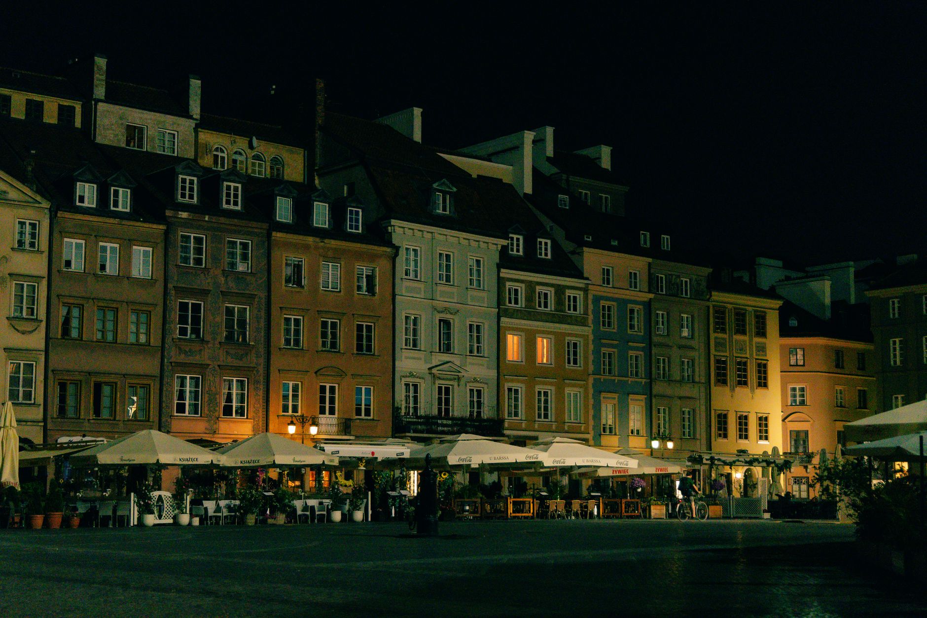 Night scene of Warsaw's Old Town Square with illuminated historic buildings.