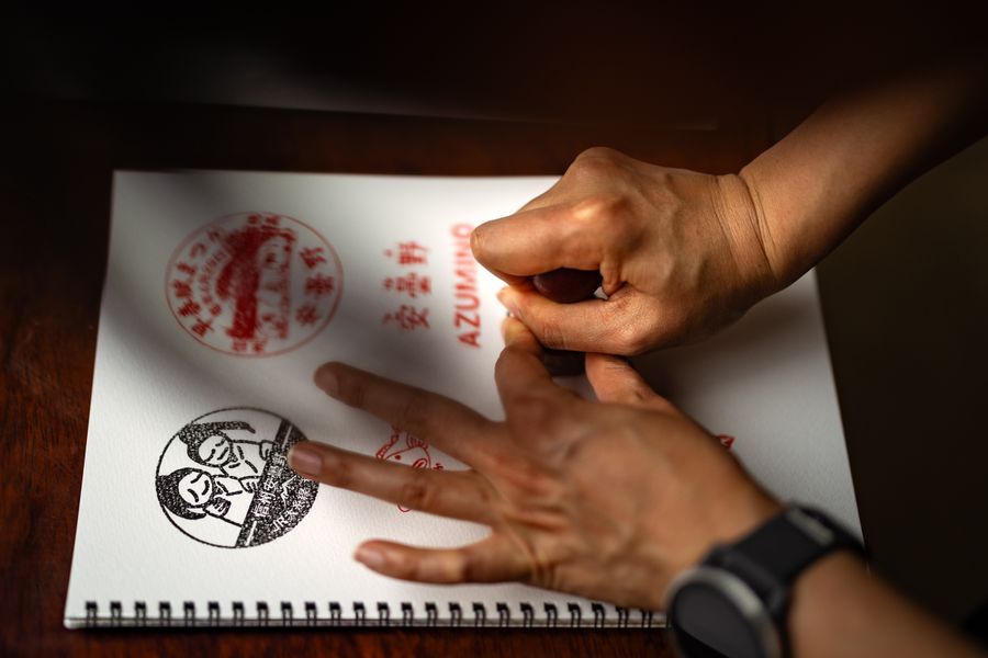 Hands stamping intricate designs in a sketchbook, showcasing artistic precision.