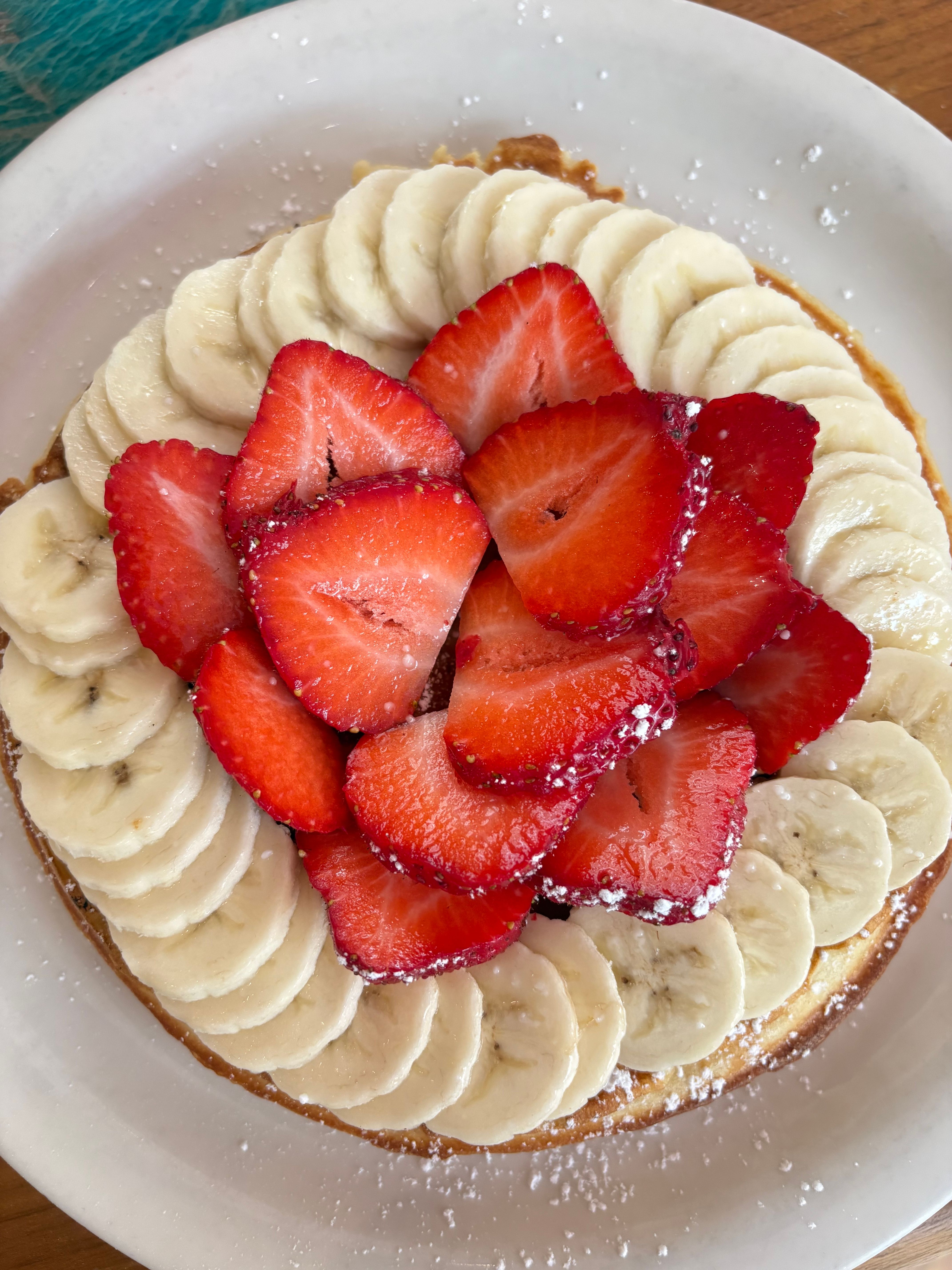 Beautifully arranged fruit tart topped with fresh bananas and strawberries.