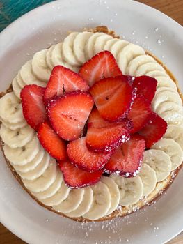 Beautifully arranged fruit tart topped with fresh bananas and strawberries.