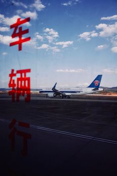 Airplane on runway with Chinese characters overlay under a bright blue sky.