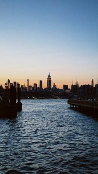 Captivating NYC skyline at sunset with the iconic Empire State Building reflecting over the water.