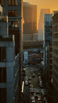 Urban view of Lower Manhattan at sunset with towering skyscrapers and a busy street.