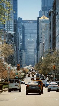 Vibrant city street scene in spring, showcasing cars and skyscrapers with the iconic MetLife Building in New York City.