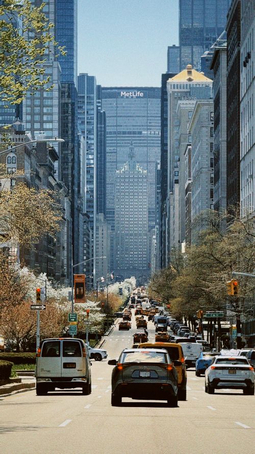 Free Vibrant city street scene in spring, showcasing cars and skyscrapers with the iconic MetLife Building in New York City. Stock Photo