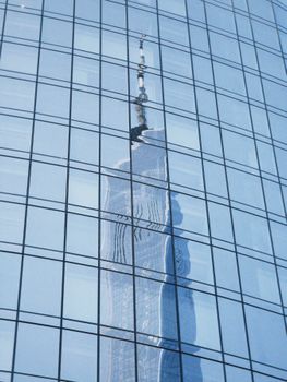 One World Trade Center reflected in curved glass windows, showcasing modern architecture.
