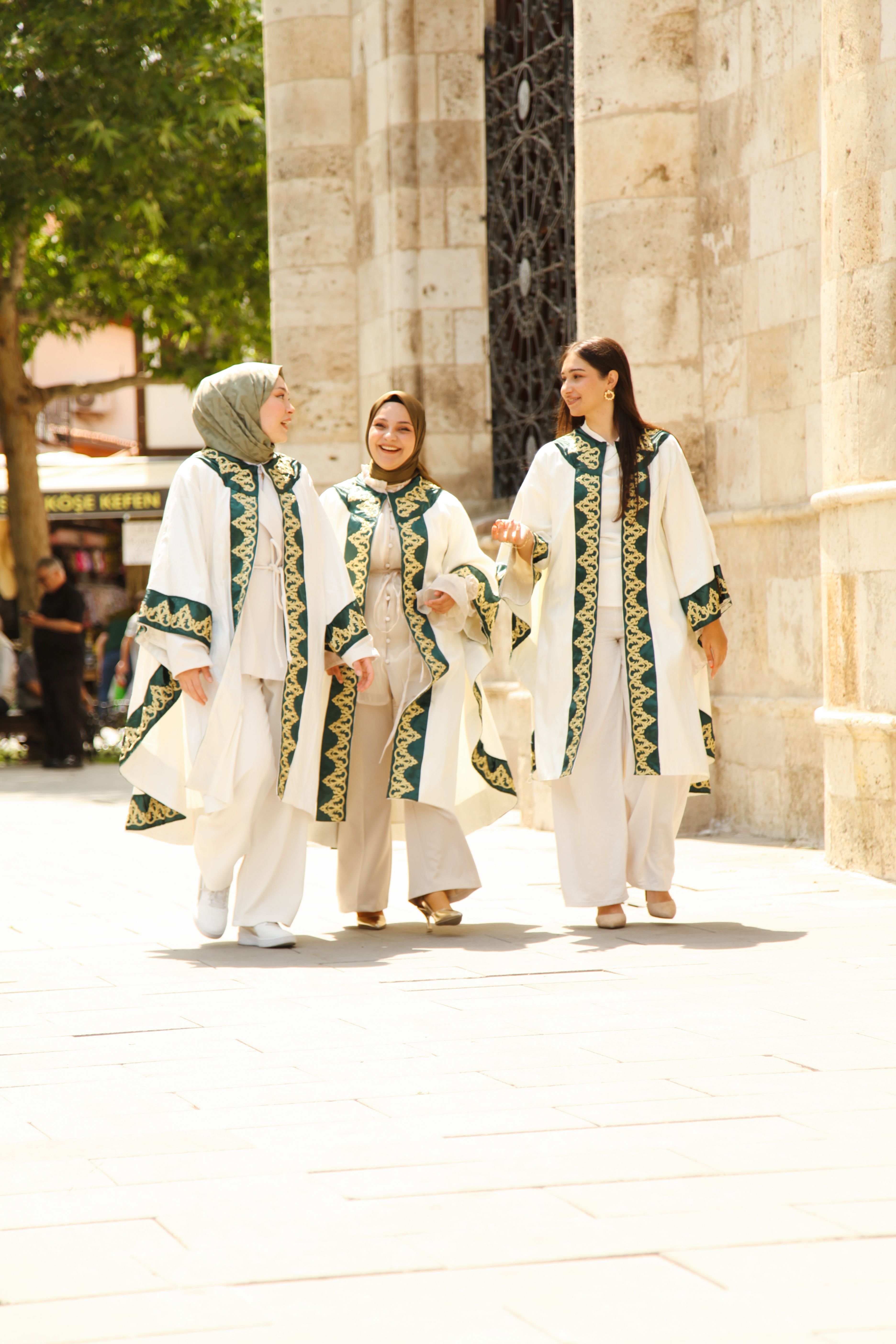 Three women in graduation robes celebrate outdoors, symbolizing achievement.