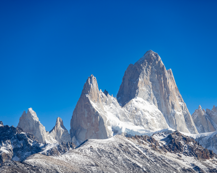 Breathtaking view of the snow-capped Fitz Roy mountains under a clear blue sky in El Chalten, Argentina.