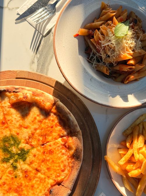 Free Tantalizing Italian dishes featuring cheese pizza, penne pasta and fries, perfect for a gourmet meal. Stock Photo