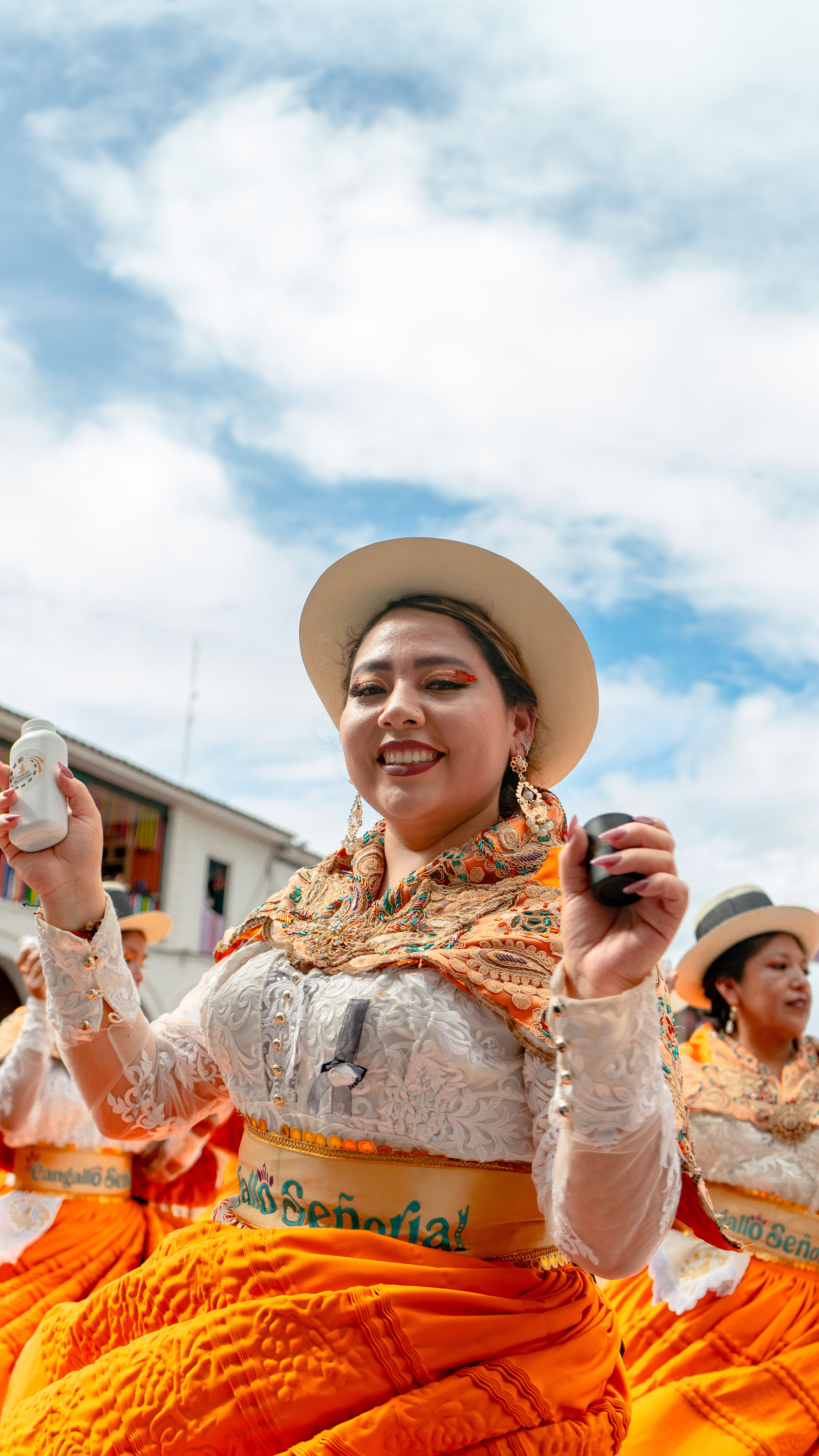 Women in traditional attire dancing joyfully at an outdoor cultural festival.