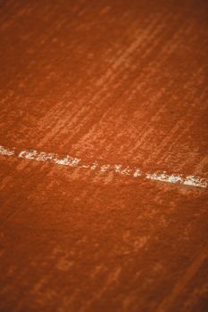 Detailed close-up of the texture on a clay tennis court line, showcasing the red surface and white marking.