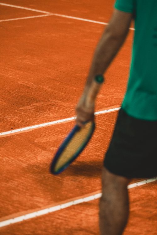 Free A player holding a racket on a clay tennis court, ready to start the game. Stock Photo