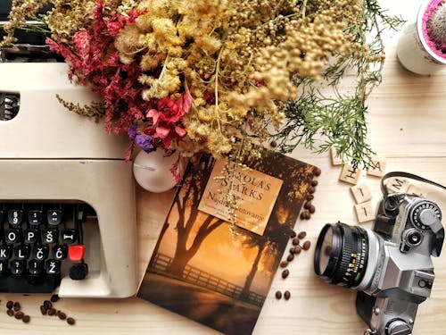 Ramo De Flores Y Libro Dispuestas Sobre Mesa De Madera Con Cámara Y Máquina De Escribir Vintage