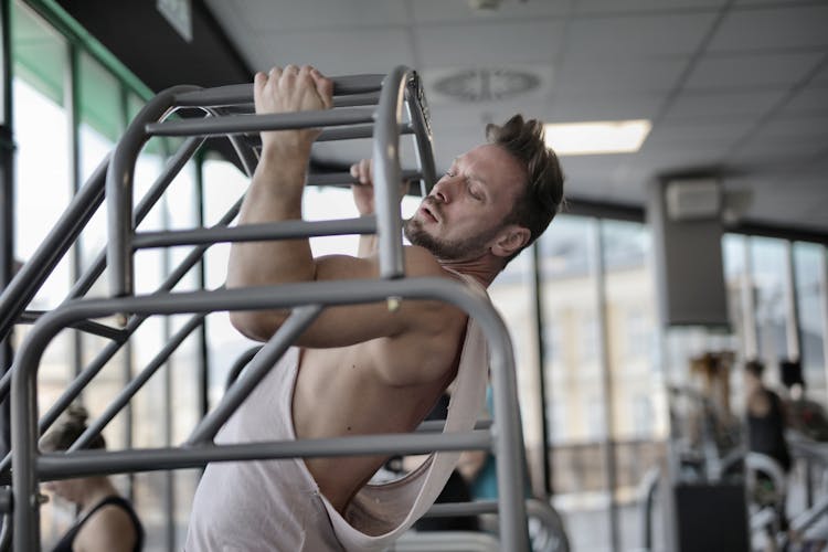 Strong Male Athlete Pulling Up On Bar In Gym