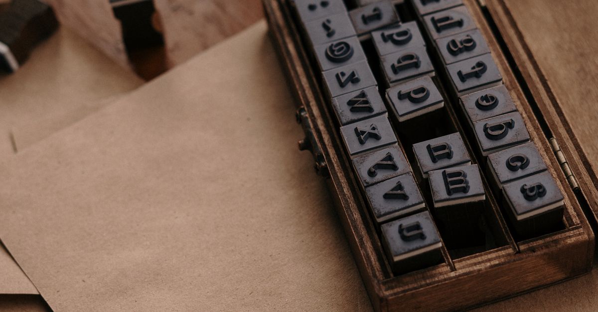 A vintage set of letter stamps on a wooden desk with twine and envelopes, perfect for handmade crafts and writing.