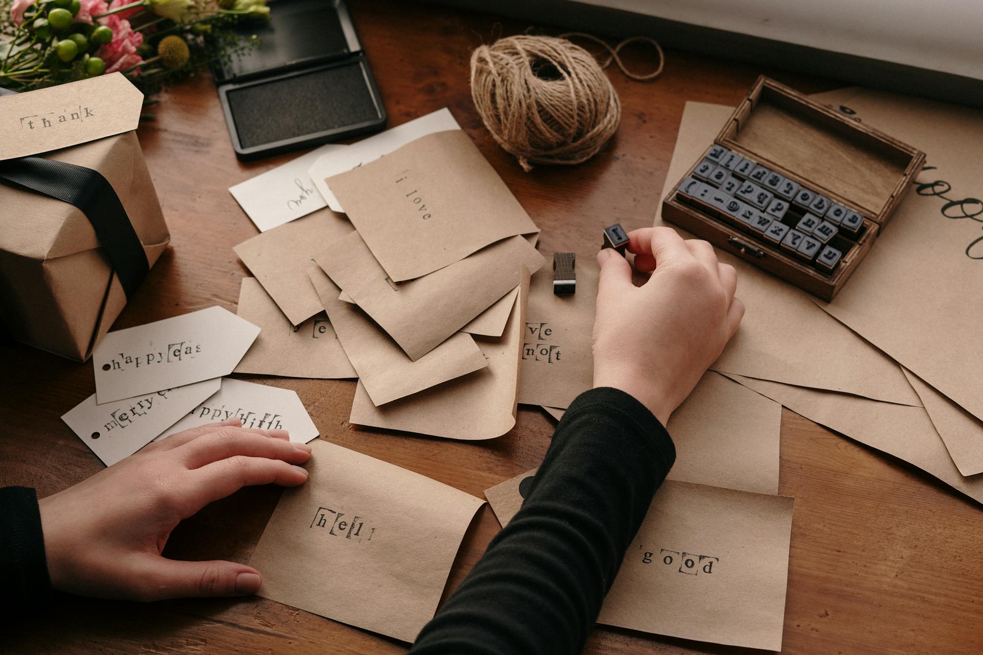 A person stamping envelopes with letters for handmade cards, showcasing creativity and craftsmanship.