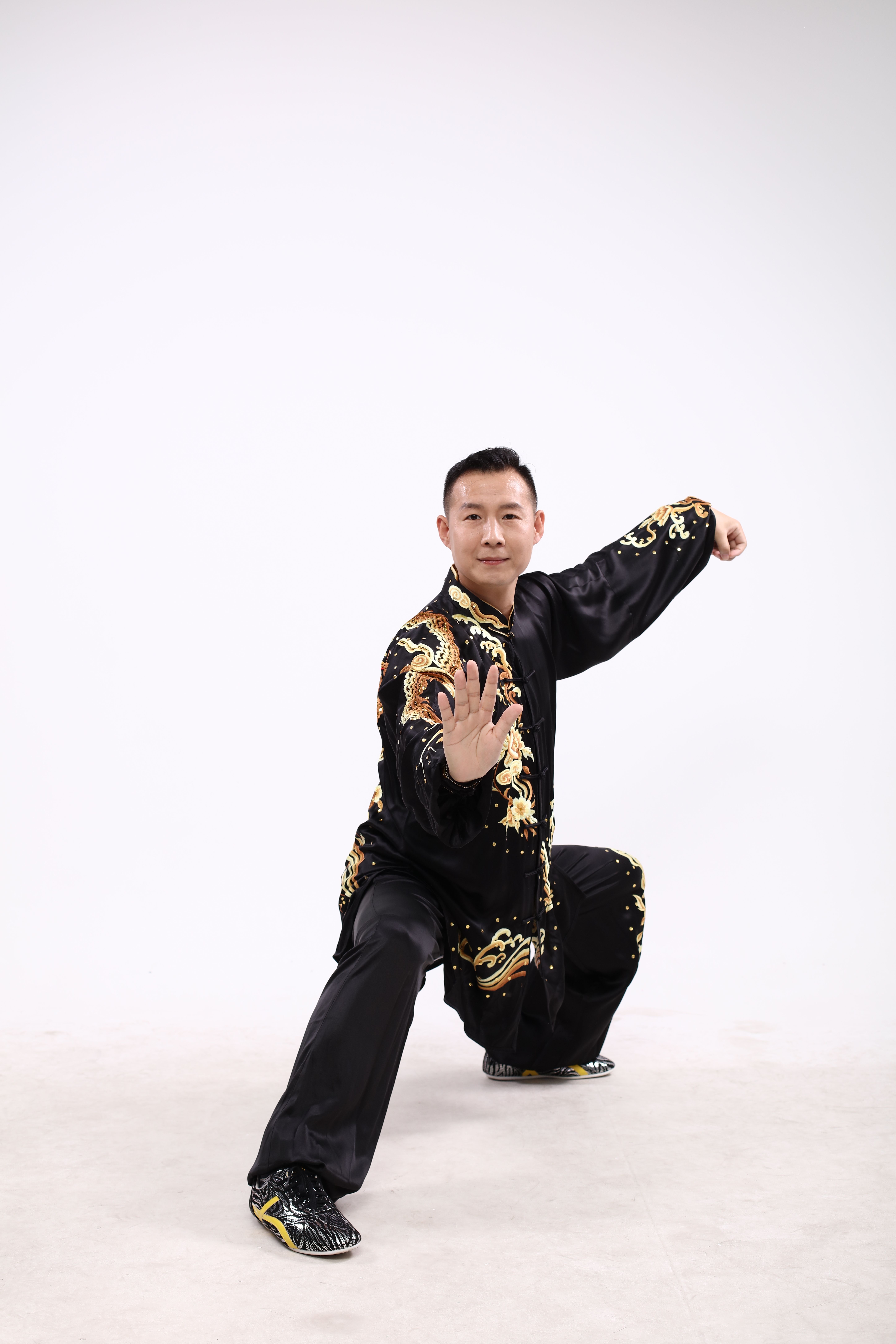 Man demonstrating a martial arts pose in elegant black traditional attire.