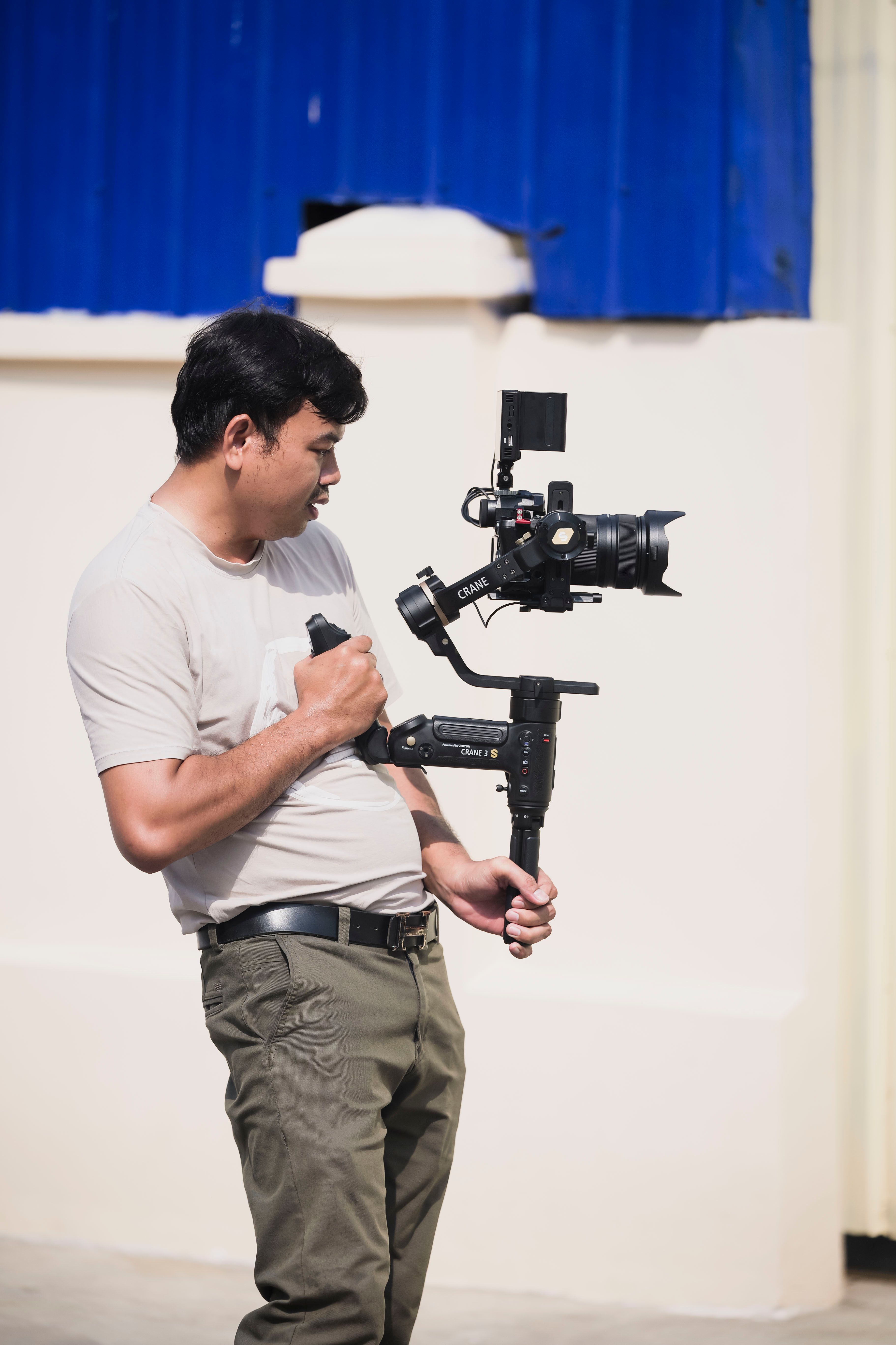 Videographer using a stabilizer and camera for outdoor filming on a sunny day.