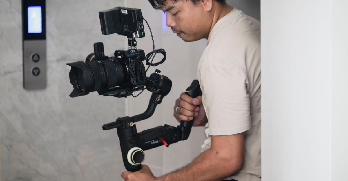 A videographer using a stabilizer indoors, focusing on precision filming.