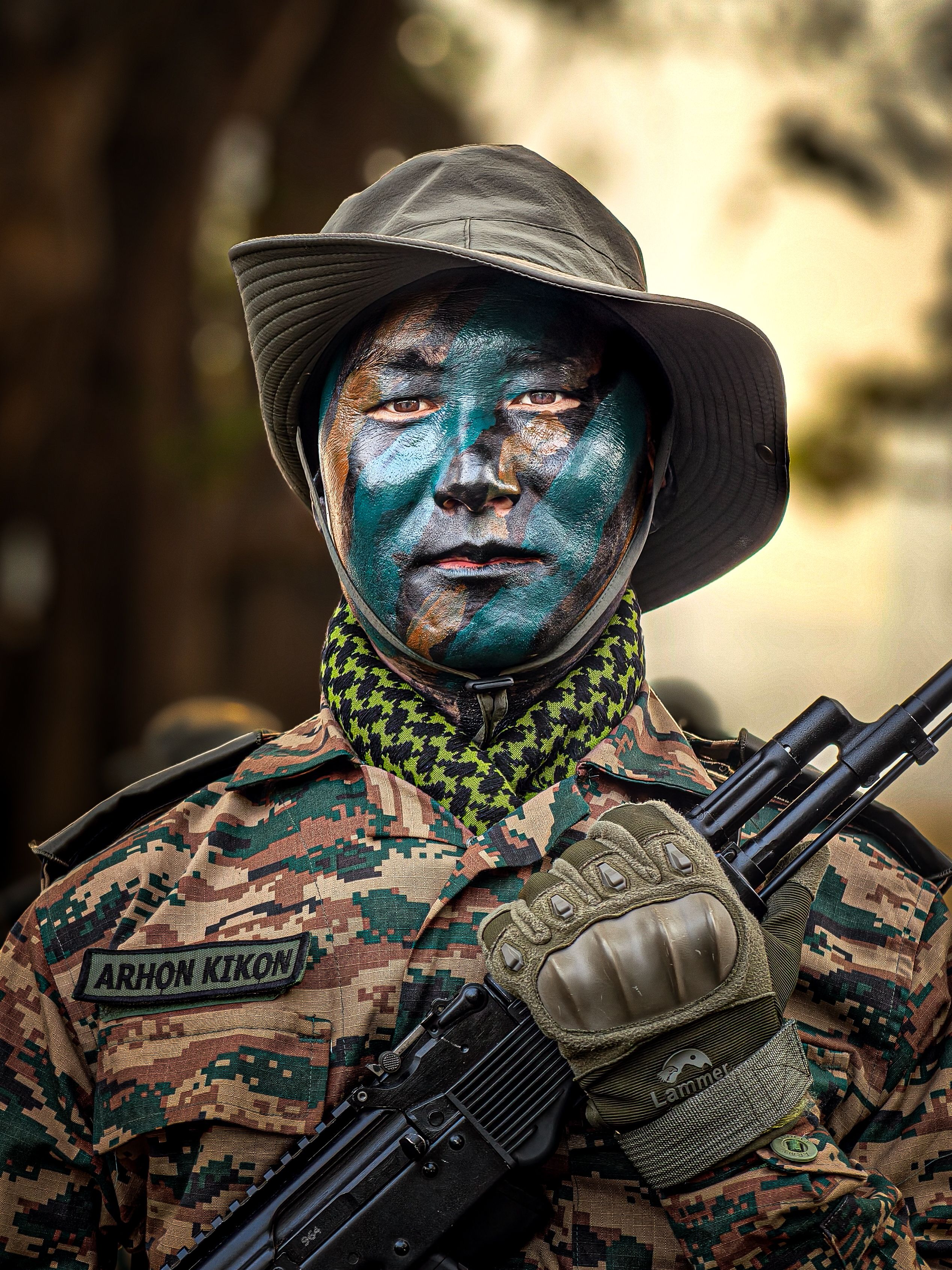 Portrait of a soldier with camouflage paint and tactical gear in a natural outdoor setting.